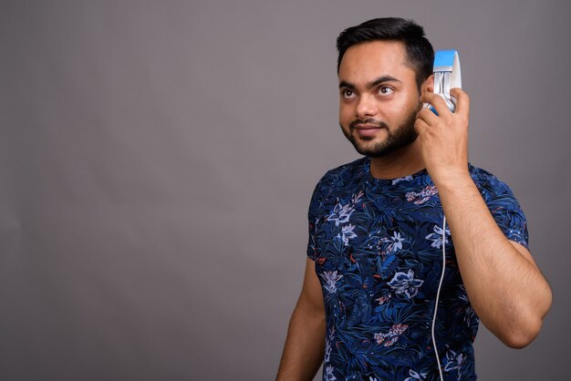 Jeune homme barbu écoutant de la musique contre le gris