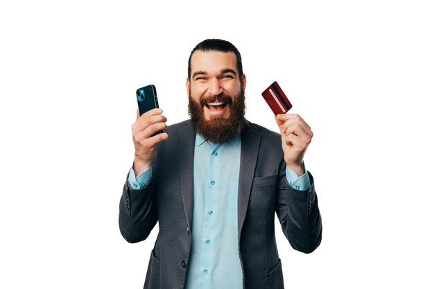 Un jeune homme barbu est enthousiasmé par les services bancaires mobiles et les remises en argent avec une nouvelle carte