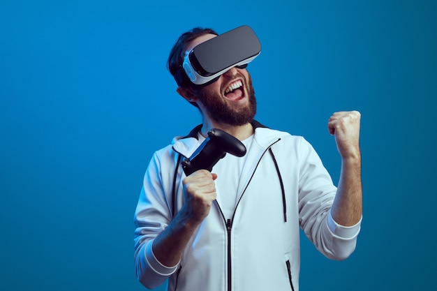 Jeune homme barbu excité debout avec l'équipement vr et jouant