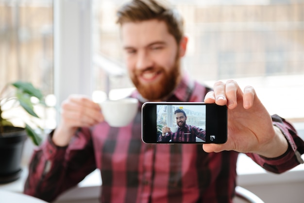 Jeune homme barbu faire un selfie par téléphone mobile