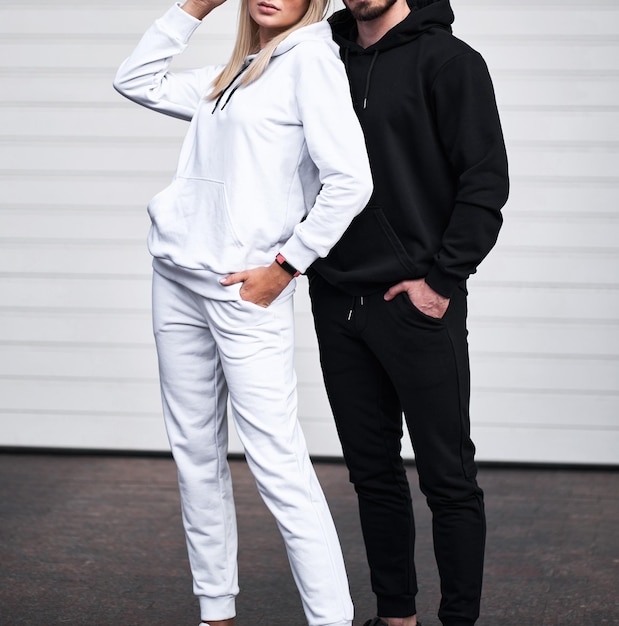 Jeune homme barbu et fille blonde se tient dans un sweat à capuche uni pour l'impression de logo Maquette de vêtements pour sweat à capuche Streetwear pour jeunes d'automne