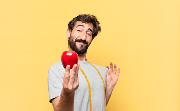 Jeune homme barbu fou au régime expression heureuse et tenant une pomme