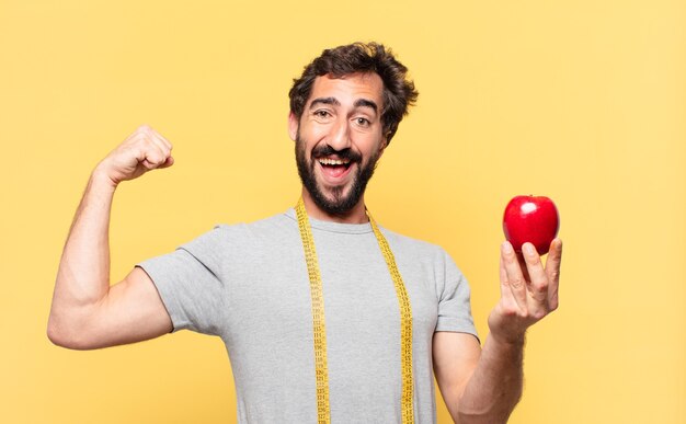 Jeune homme barbu fou au régime expression heureuse et tenant une pomme