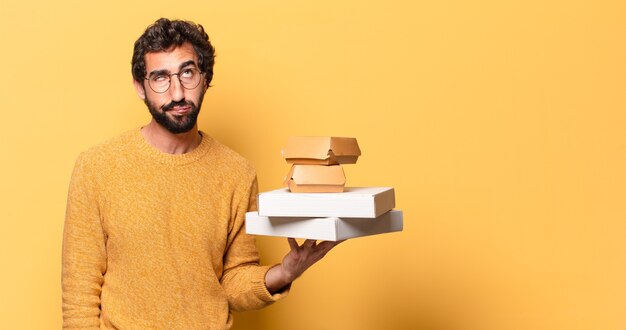 Jeune homme barbu fou ayant à emporter de la restauration rapide avec un espace de copie