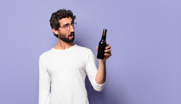 Jeune homme barbu fou avec une bière