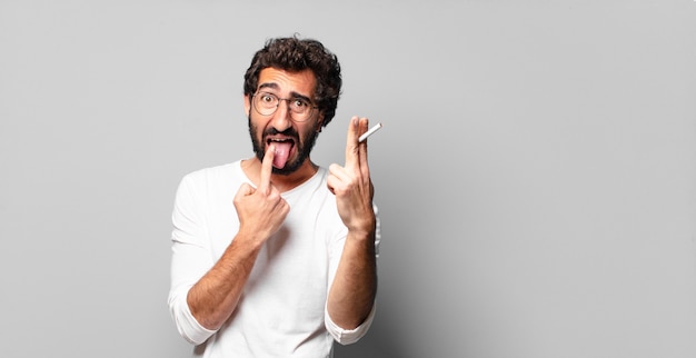 Jeune homme barbu fou avec une cigarette. pas de concept de fumer.