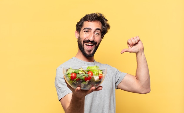 Jeune homme barbu fou avec une expression heureuse et tenant une salade