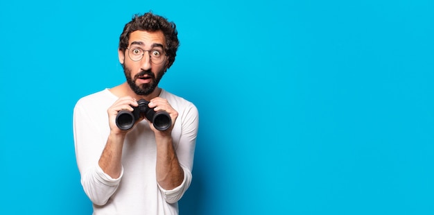 Jeune homme barbu fou avec des jumelles