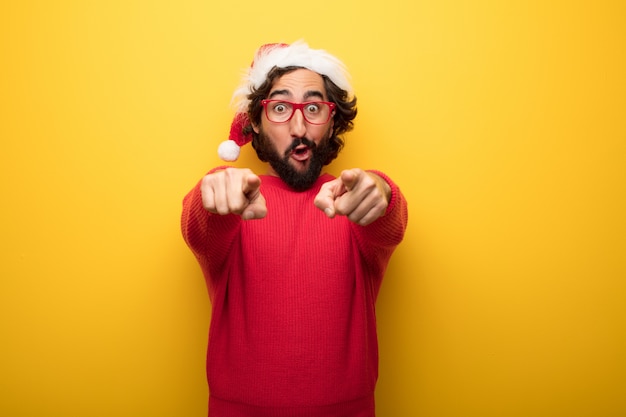 Jeune homme barbu fou portant des lunettes rouges et un chapeau de père Noël