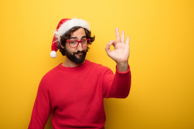 Jeune homme barbu fou portant des lunettes rouges et un chapeau de père Noël
