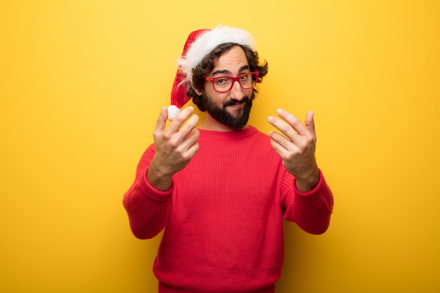 Jeune homme barbu fou portant des lunettes rouges et un chapeau de père Noël