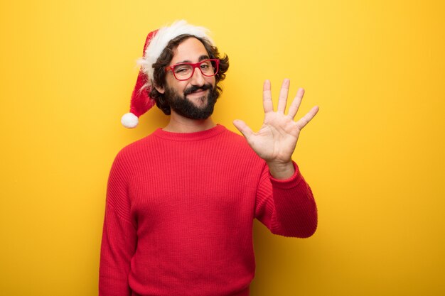 Jeune homme barbu fou portant des lunettes rouges et un chapeau de père Noël