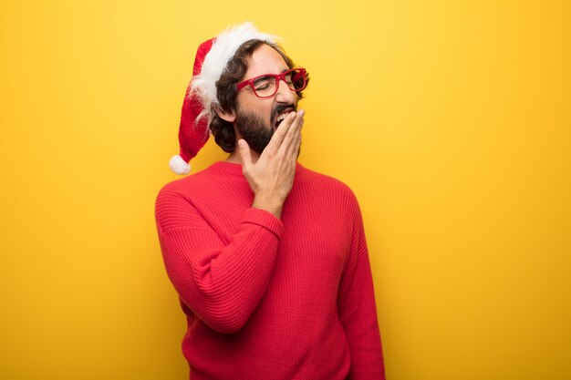 Jeune homme barbu fou portant des lunettes rouges et un chapeau de père Noël