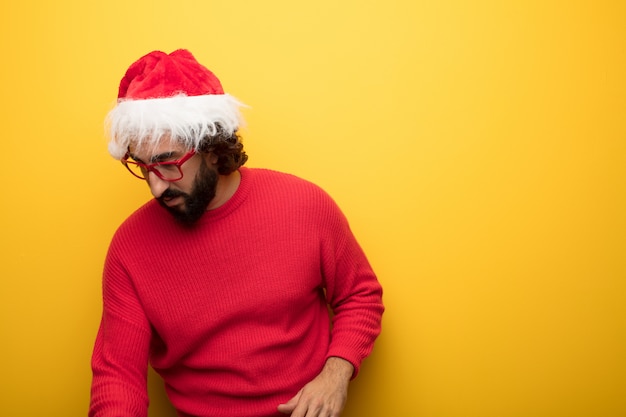 Jeune homme barbu fou portant des lunettes rouges et un chapeau de père Noël