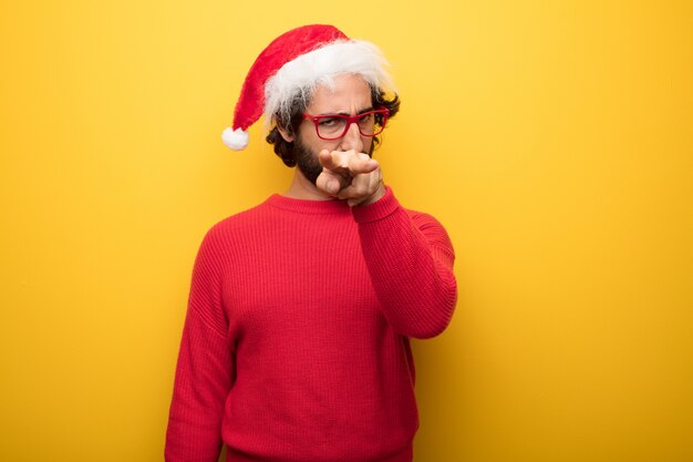 Jeune homme barbu fou portant des lunettes rouges et un chapeau de père Noël