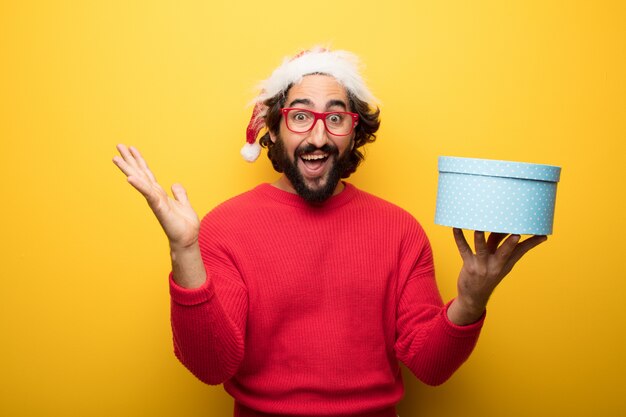 Jeune homme barbu fou portant des lunettes rouges et un chapeau de père Noël