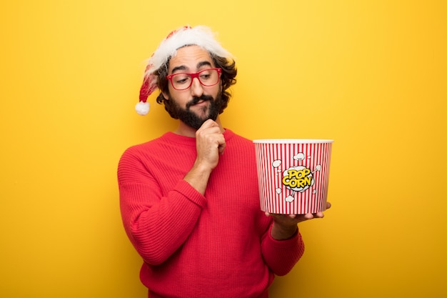 Jeune homme barbu fou portant des lunettes rouges et un chapeau de père Noël