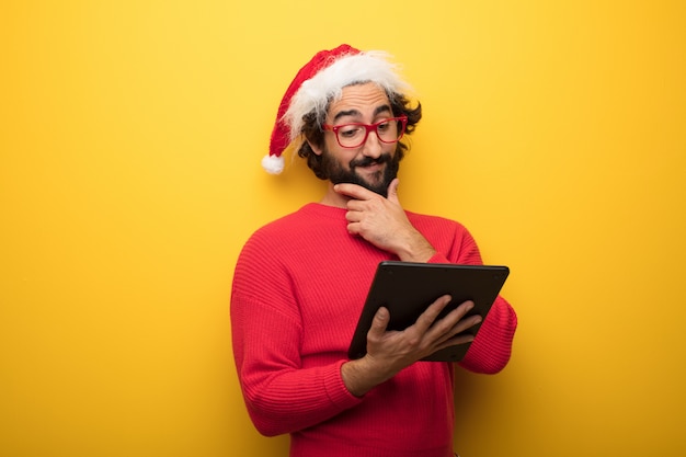 Jeune homme barbu fou portant des lunettes rouges et un chapeau de père Noël