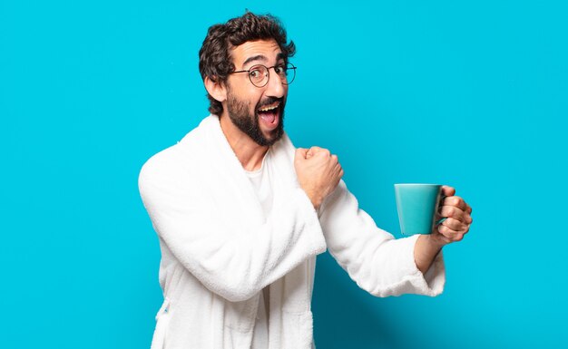 Jeune homme barbu fou portant un peignoir avec une tasse de café