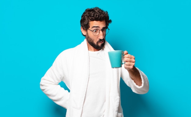 Jeune homme barbu fou portant un peignoir avec une tasse de café