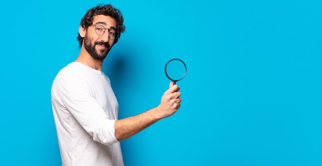 Photo jeune homme barbu fou à la recherche et en essayant de trouver avec une loupe