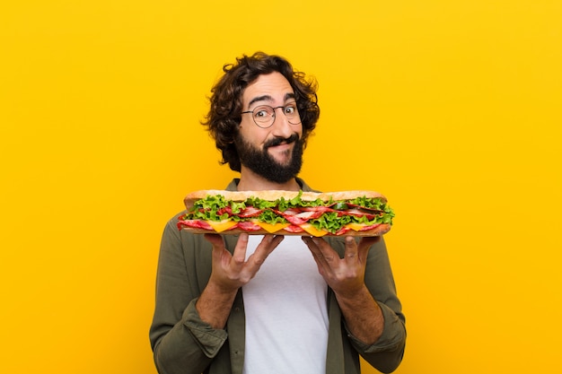 Jeune homme barbu fou avec un sandwich géant.