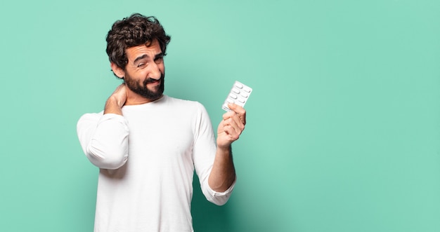 Jeune homme barbu fou avec une tablette de pilules