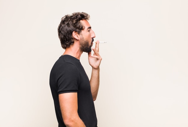 Jeune homme barbu fumant une cigarette