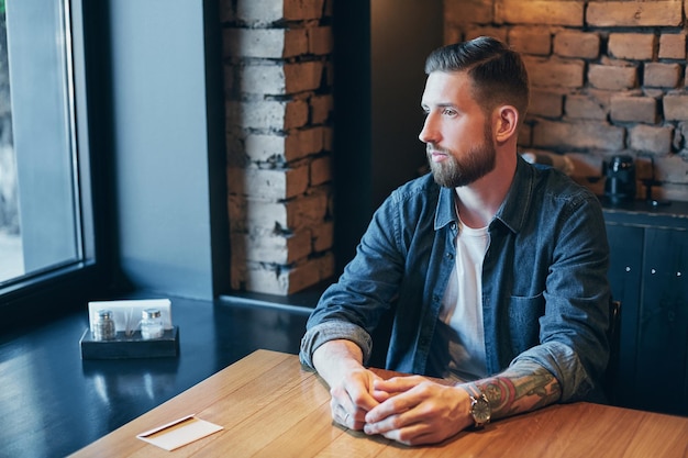 Un jeune homme barbu heureux buvant du café frais le matin.