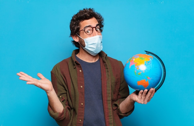 Jeune homme barbu avec un masque médical et un modèle de carte du monde
