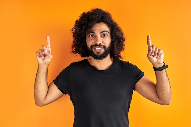 Un jeune homme barbu optimiste pointe vers le haut avec les deux index