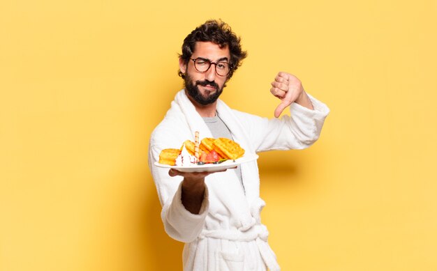 Jeune homme barbu portant un peignoir et prenant son petit déjeuner