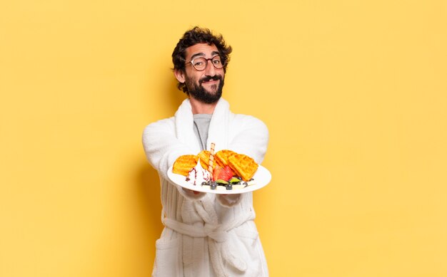 Jeune homme barbu portant un peignoir et prenant son petit déjeuner