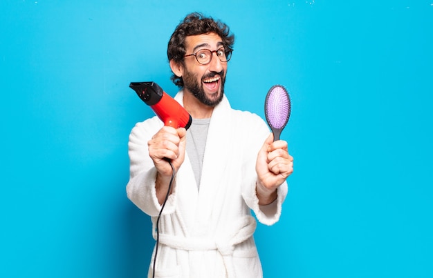 Jeune homme barbu portant un peignoir avec un sèche-cheveux