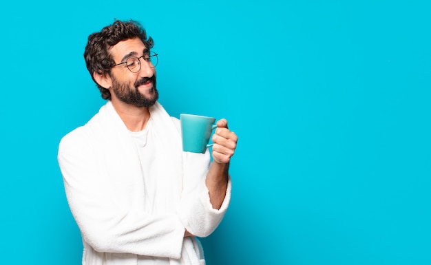 Jeune homme barbu portant un peignoir avec une tasse de café