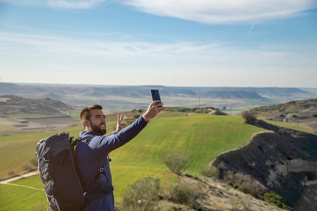 Jeune homme barbu prenant un selfie avec son smartphone