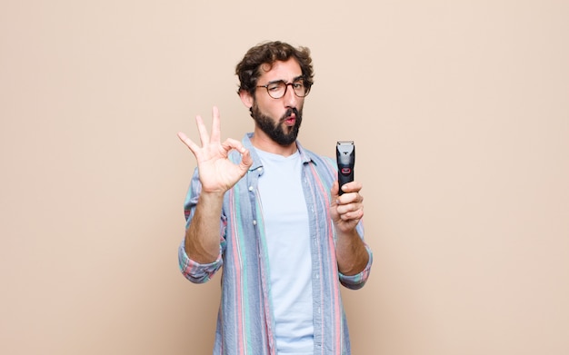 Jeune homme barbu avec un rasoir électrique