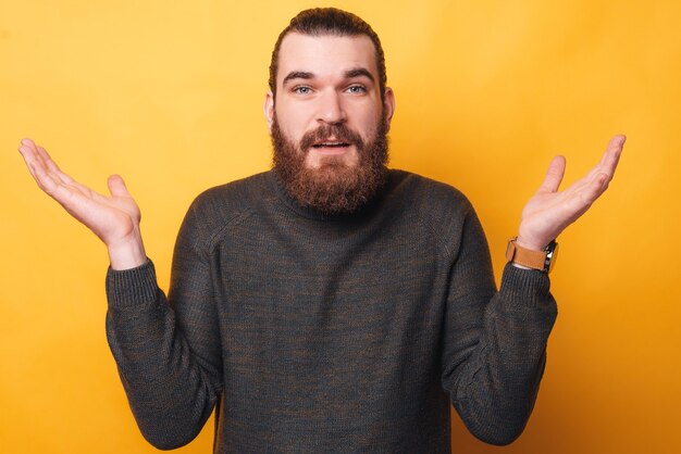 Un jeune homme barbu regarde et montre que je ne sais pas chanter est confus