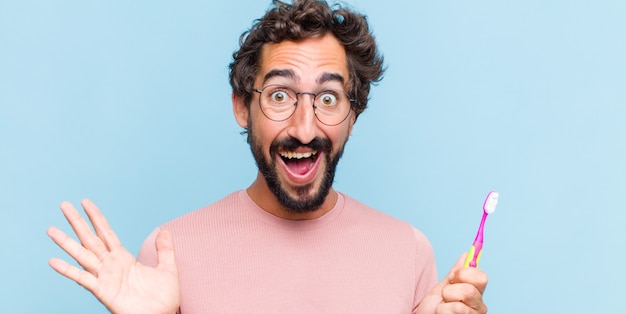 Jeune homme barbu se sentant heureux, excité, surpris ou choqué, souriant et étonné de quelque chose d'incroyable