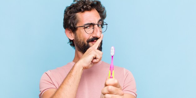 Jeune homme barbu à la sérieuse et mécontent avec les deux doigts croisés à l'avant dans le rejet, demandant le silence