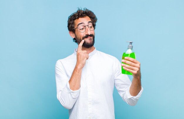 Jeune homme barbu souriant joyeusement et rêvassant ou doutant, regardant sur le côté