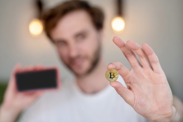 Jeune homme barbu tenant un bitcoin à la main