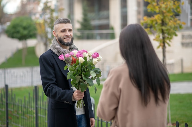 Jeune homme barbu tenant des fleurs en venant pour une date