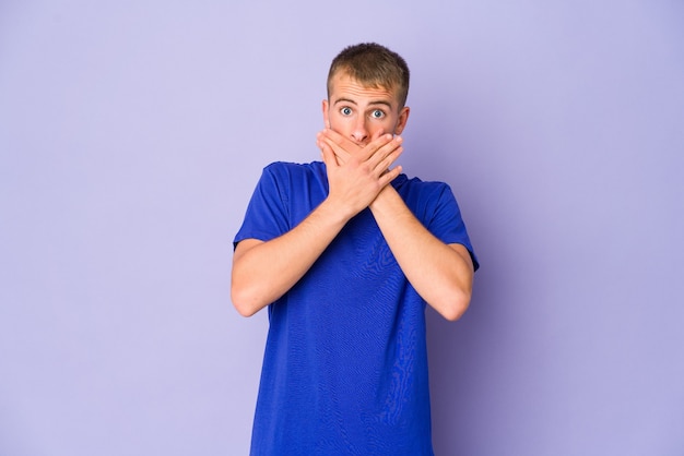 Jeune homme beau caucasien choqué couvrant la bouche avec les mains.