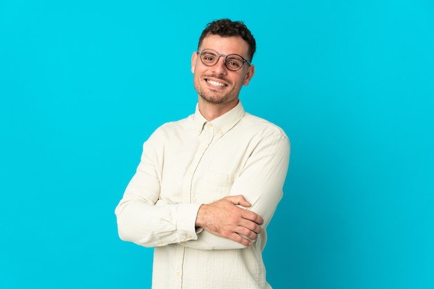 Jeune homme beau caucasien isolé sur bleu avec les bras croisés et impatient