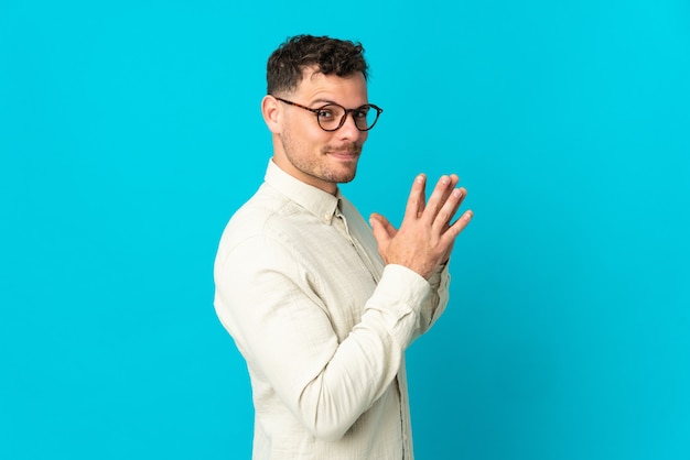 Jeune homme beau caucasien isolé sur quelque chose de complot bleu