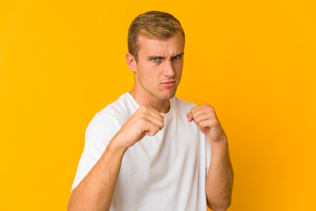 Jeune homme beau caucasien jetant un coup de poing, colère, combat en raison d'une dispute, boxe.