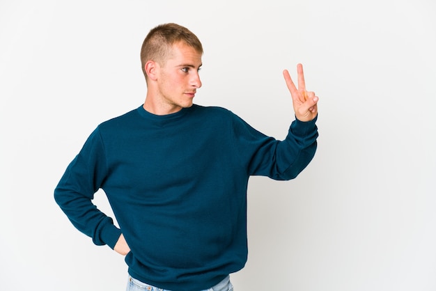 Jeune homme beau caucasien joyeux et insouciant montrant un symbole de paix avec les doigts.