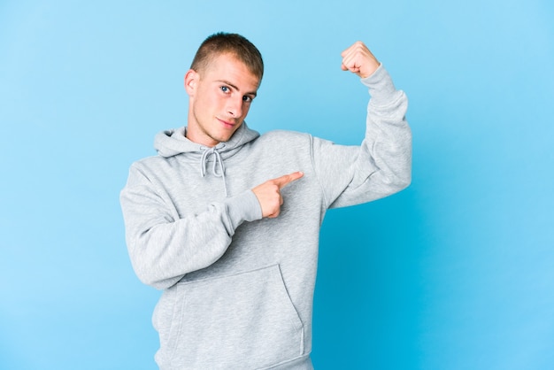 Jeune homme beau caucasien montrant le geste de force avec les bras, symbole du pouvoir féminin