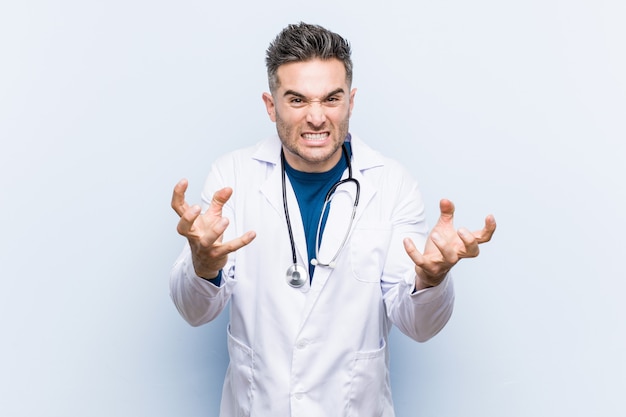 Jeune homme beau docteur bouleversé crier avec les mains tendues.